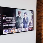 Smart TV exibindo conteúdo de streaming em uma sala de estar moderna com parede de tijolos aparentes