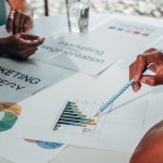 Equipe reunida em um escritório analisa gráficos, documentos e dados para desenvolver uma estratégia de marketing.