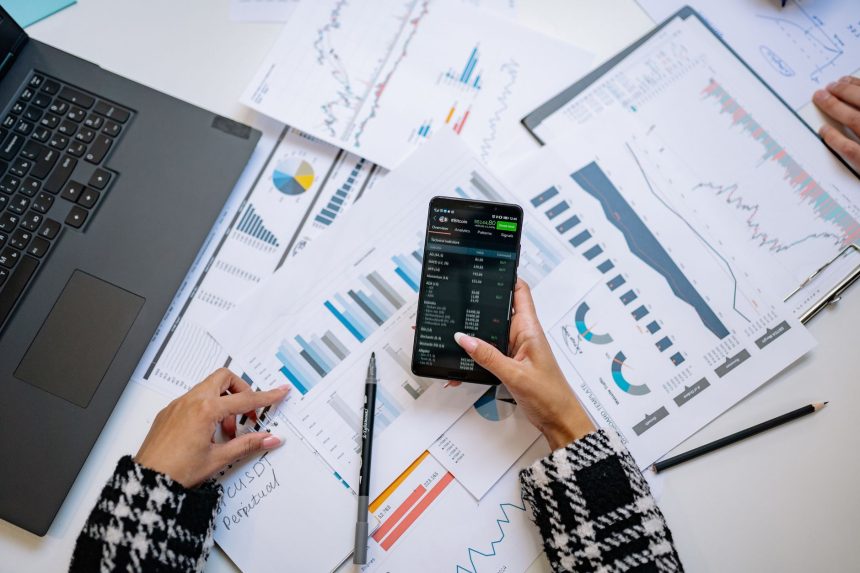Vista superior de gráficos e um smartphone sobre uma mesa de escritório, representando análise de dados digitais.