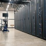 Racks com servidores, equipamentos de rede e cabos em um data center moderno.