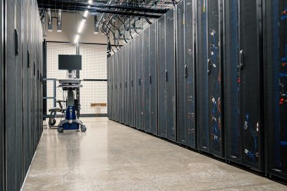 Sala de data center com racks metálicos, servidores, equipamentos de rede e cabos.